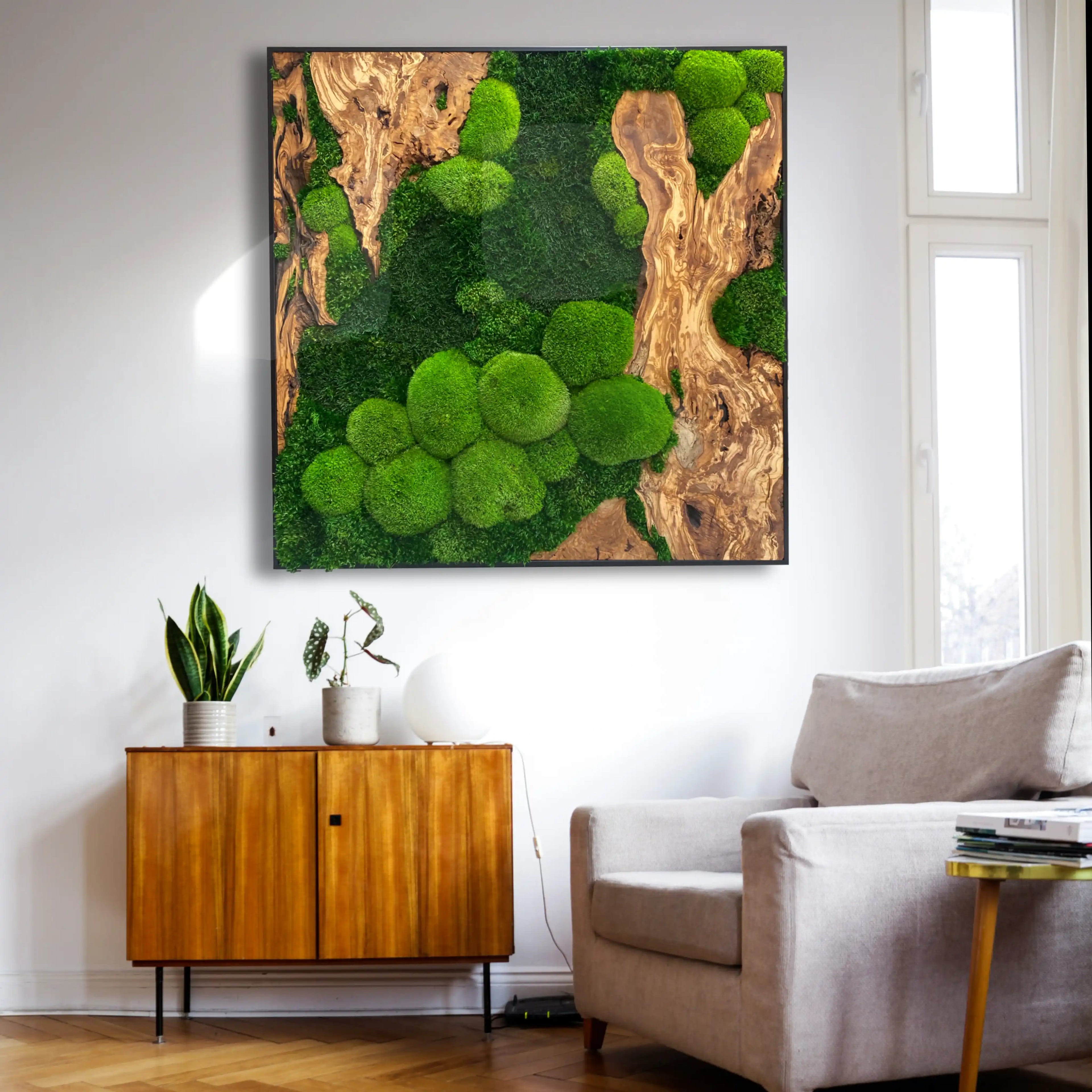 Handgemachtes Moosbild „Olive quadratisch“ in einem schwarzen Rahmen - eine stilvolle Wanddekoration aus grünen Moosen und edlem Olivenholz in einem stilvoll eingerichteten Raum.