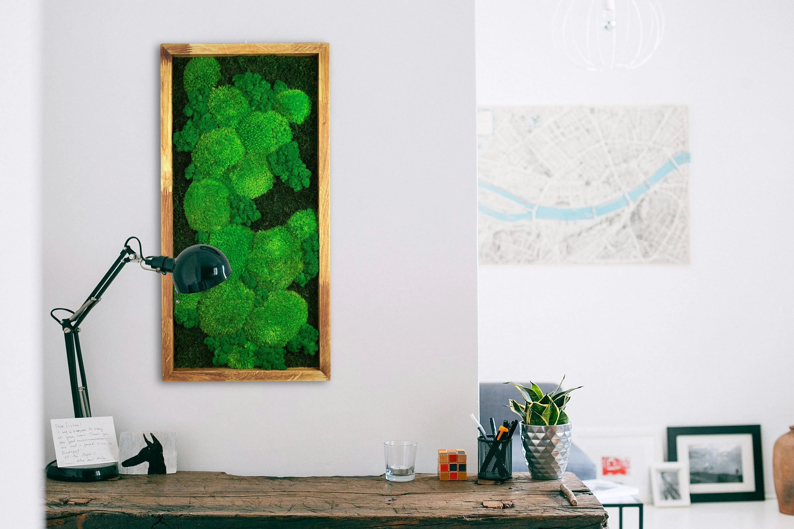 Handgemachtes Moosbild mit dem Namen "Growth" in einem Echtholzrahmen über einem rustikalen Schreibtisch.