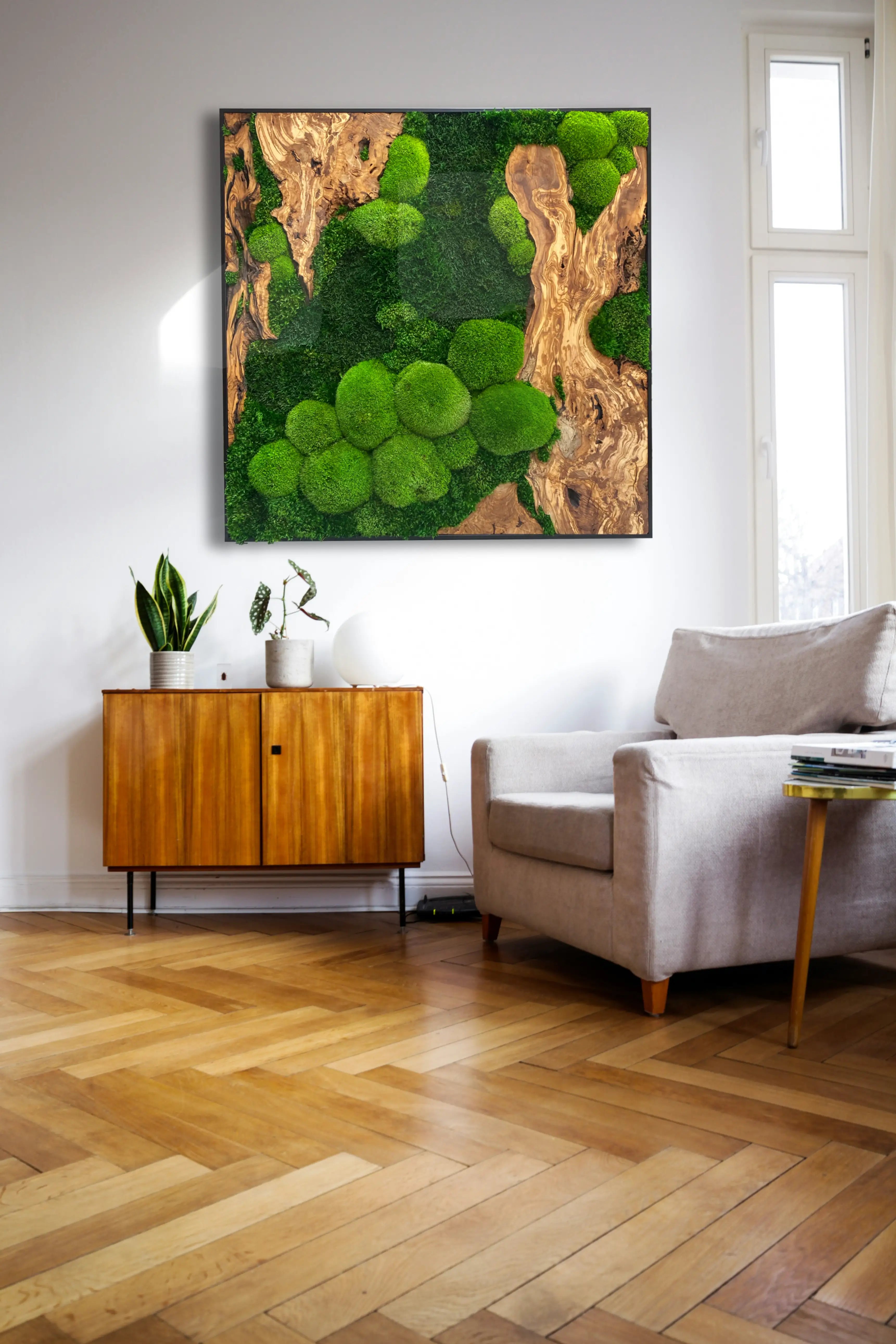 Handgemachtes Moosbild „Olive quadratisch“ in einem schwarzen Rahmen - eine stilvolle Wanddekoration aus grünen Moosen und edlem Olivenholz in einem stilvoll eingerichteten Raum.